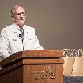 Man in white coat speaking at podium