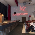 Ceremony stage with crowd of people in white coats