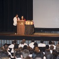 Two speakers stand at podium in front of a large crowd