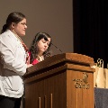 Two speakers stand at podium