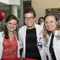 Three people wearing white coats pose for a photo