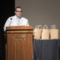 man at podium with multicolored tie